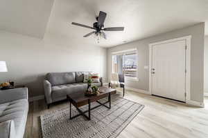 Living room featuring light hardwood / wood-style floors, a textured ceiling, and ceiling fan