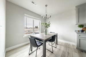 Dining area with light hardwood / wood-style floors and a notable chandelier