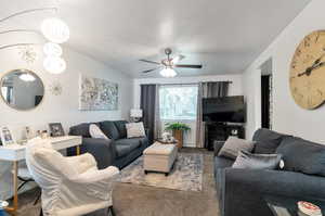 Living room with a textured ceiling, carpet, and ceiling fan