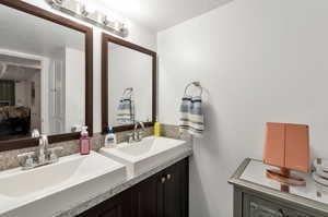 Bathroom featuring a textured ceiling and dual bowl vanity