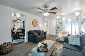 Carpeted living room with plenty of natural light, a textured ceiling, and ceiling fan