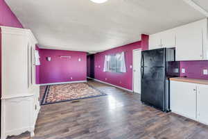 Kitchen with black refrigerator, white cabinets, and dark hardwood / wood-style floors