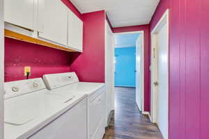 Washroom featuring separate washer and dryer, cabinets, and dark hardwood / wood-style floors