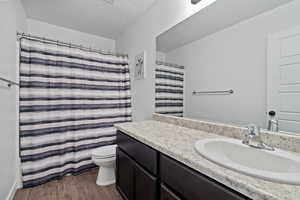 Bathroom featuring vanity, a textured ceiling, wood-type flooring, and toilet