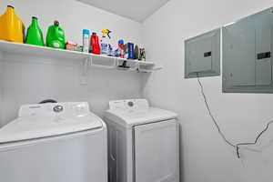 Laundry area with washer and clothes dryer, a textured ceiling, and electric panel