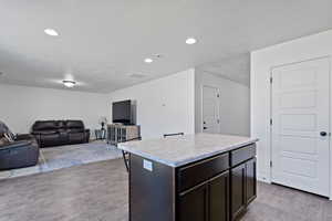 Kitchen featuring dark brown cabinets, a center island, hardwood / wood-style floors, and a textured ceiling