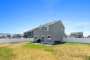 Rear view of property with central AC unit, a patio, and a yard