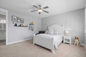 Bedroom with sink, ensuite bathroom, light colored carpet, and ceiling fan