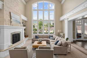 Living room featuring light hardwood / wood-style flooring, a fireplace, and a towering 25' barrel ceiling