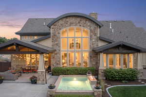 Back house at dusk featuring a patio area, outdoor lounge area, and a hot tub