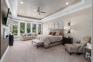 Carpeted bedroom featuring a raised ceiling and ceiling fan  Automatic shades.