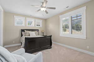 Bedroom with multiple windows, ceiling fan, and light colored carpet