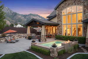 Back house at dusk with a mountain view, a patio, and an outdoor living space with a fire pit