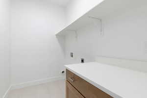 Clothes washing area featuring light tile patterned flooring, cabinets, electric dryer hookup, and washer hookup