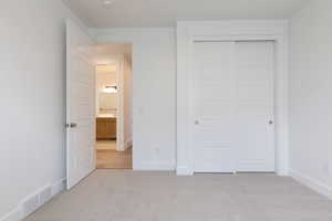 Unfurnished bedroom with light colored carpet and a closet