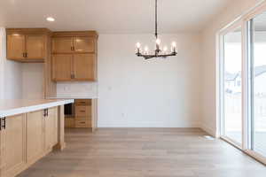 Kitchen featuring an inviting chandelier, backsplash, a healthy amount of sunlight, and light hardwood / wood-style floors