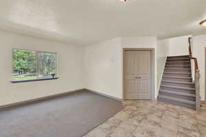 Carpeted room featuring a textured ceiling, double doors lead to office/bedroom.