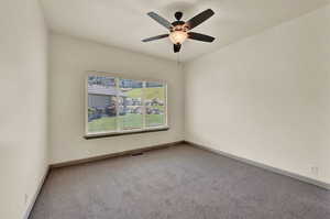 Carpeted spare room featuring ceiling fan