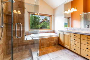 Primary Bathroom featuring shower with separate bathtub, tile patterned floors, vanity, and high vaulted ceiling