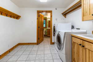 Laundry area featuring cabinets, light tile patterned flooring, and independent washer and dryer, mud room off the garage.