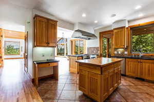 Kitchen with tile patterned floors, tasteful backsplash, sink, a kitchen island, and island range hood