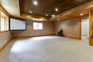 Carpeted empty room with wood ceiling, a raised ceiling, and a wealth of natural light