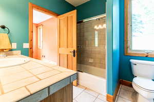 Full bathroom featuring tile patterned floors, toilet, vanity, and tiled shower / bath