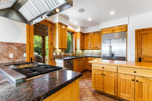 Kitchen with premium range hood, tasteful backsplash, sink, appliances with stainless steel finishes, and light tile patterned floors