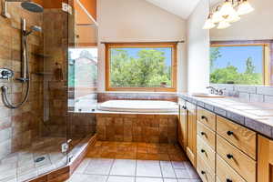 PrimaryBathroom with tile patterned flooring, lofted ceiling, independent shower and bath, and vanity