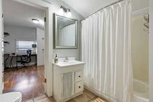 Full bathroom featuring vanity, hardwood / wood-style floors, shower / bath combo, toilet, and lofted ceiling