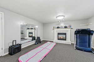 Workout area with carpet floors, a fireplace, and a textured ceiling