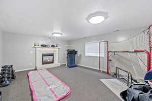 Workout room featuring a fireplace, carpet floors, and a textured ceiling