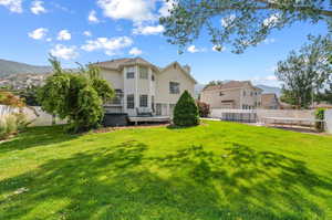 Back of house featuring a wooden deck and a lawn