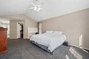 Carpeted bedroom featuring a closet, lofted ceiling, ceiling fan, and a walk in closet