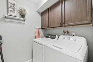 Laundry area with washer and clothes dryer and cabinets