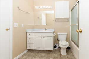 Full bathroom featuring vanity, tile patterned flooring, bath / shower combo with glass door, and toilet