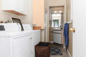 Washroom featuring washer and clothes dryer, cabinets, and light tile patterned floors