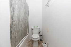 Bathroom featuring toilet, shower / bath combo, and tile patterned flooring