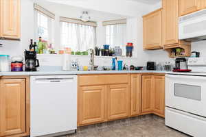 Kitchen featuring light tile patterned flooring, sink, light brown cabinetry, and white appliances