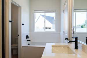 Bathroom featuring a bath, sink, and toilet