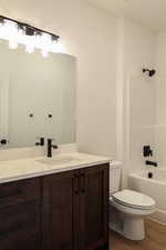 Full bathroom featuring wood-type flooring, tub / shower combination, vanity, and toilet