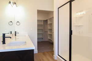 Bathroom with a shower with shower door, vanity, and hardwood / wood-style flooring