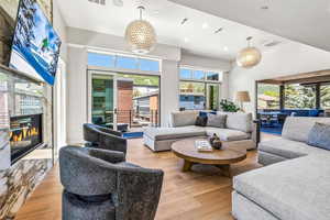 Living room with light wood-type flooring, a notable chandelier, and a healthy amount of sunlight