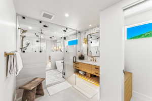 Bathroom with tile patterned flooring, tile walls, plus walk in shower, and vanity