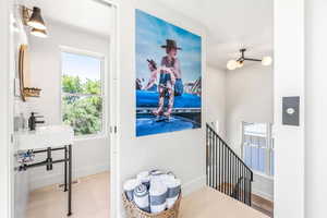 Hallway with sink, light hardwood / wood-style flooring, and a wealth of natural light