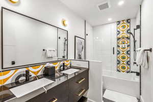 Bathroom featuring tile patterned floors, shower / bath combination with glass door, and dual bowl vanity