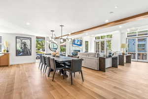 Dining area with a chandelier, a fireplace, a healthy amount of sunlight, and light wood-type flooring