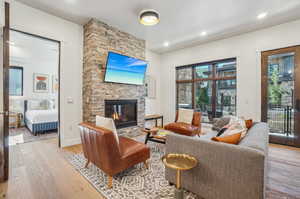 Living room with light hardwood / wood-style flooring and a stone fireplace