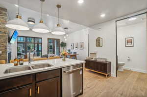 Kitchen featuring sink, dishwasher, hanging light fixtures, and light hardwood / wood-style floors