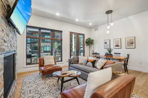 Living room with a stone fireplace and light hardwood / wood-style floors